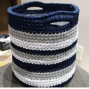 Large round crocheted t-shirt yarn storage basket with built-in handles, featuring alternating stripes of navy blue, light grey, and white.